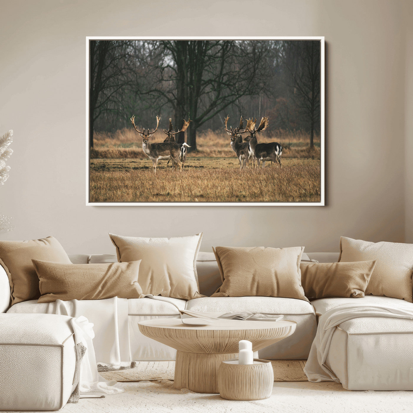 A group of majestic deer standing in a golden field with bare trees in the background, creating a peaceful woodland scene.