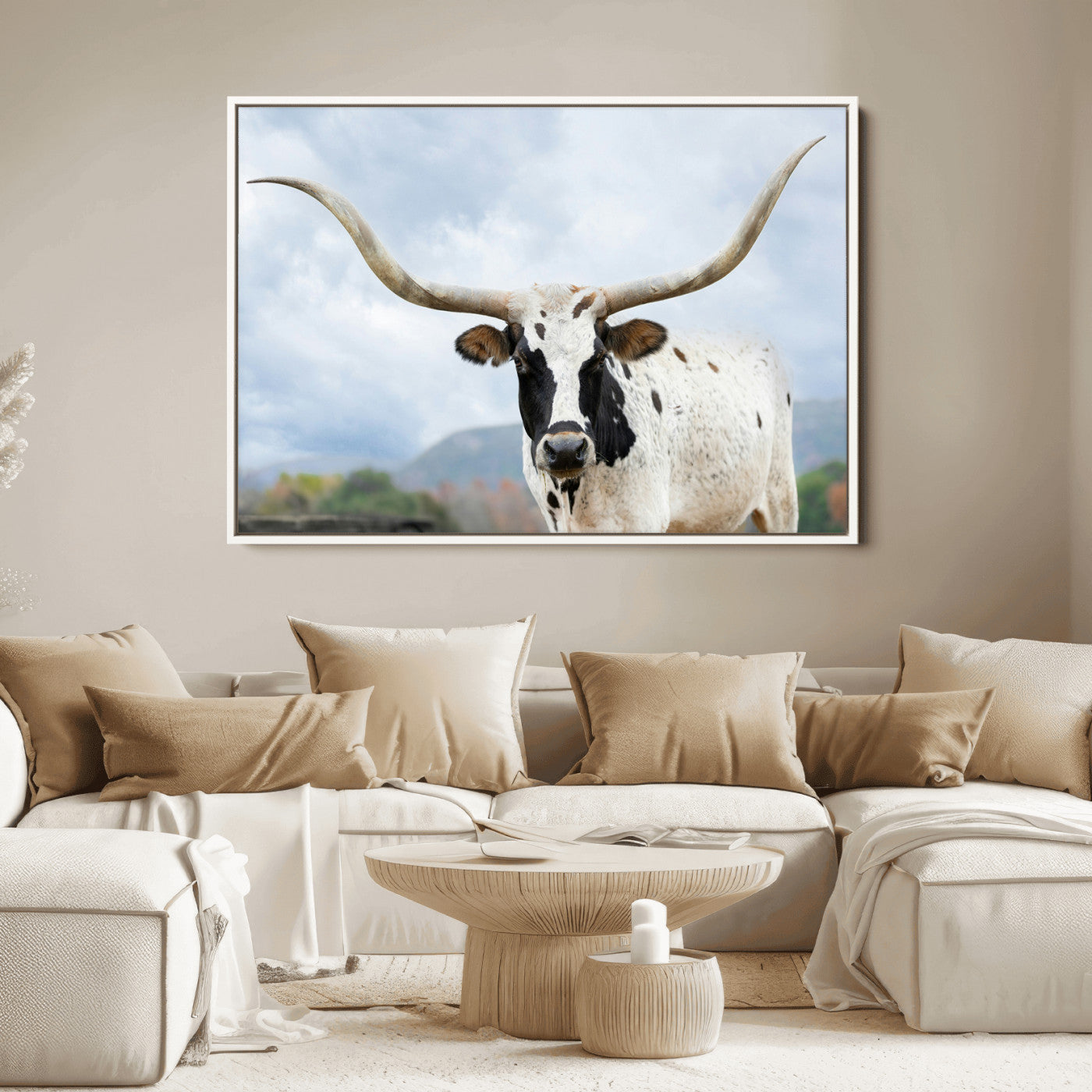 Close-up of a Texas Longhorn with curved horns, black and white markings, set against a cloudy sky and distant hills, perfect for rustic decor.