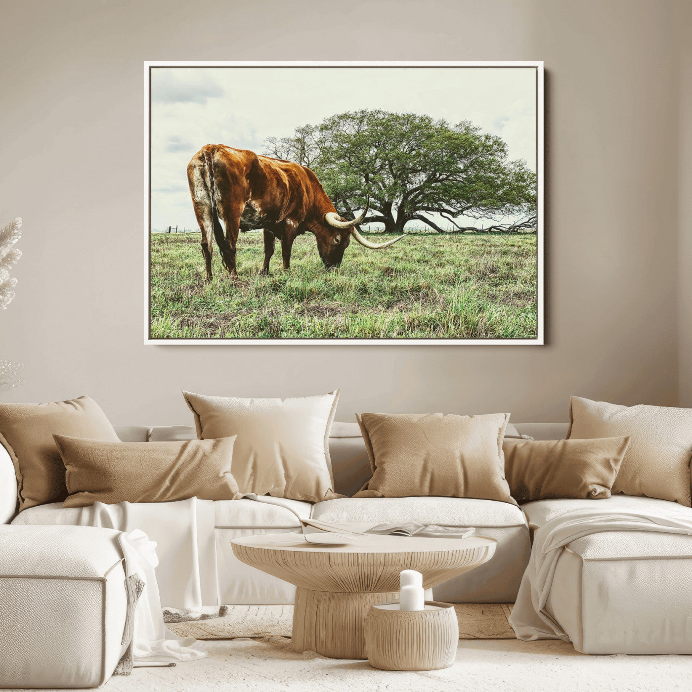 A Texas Longhorn grazing in a green pasture with a large tree in the background, evoking a rustic Western and farmhouse aesthetic.