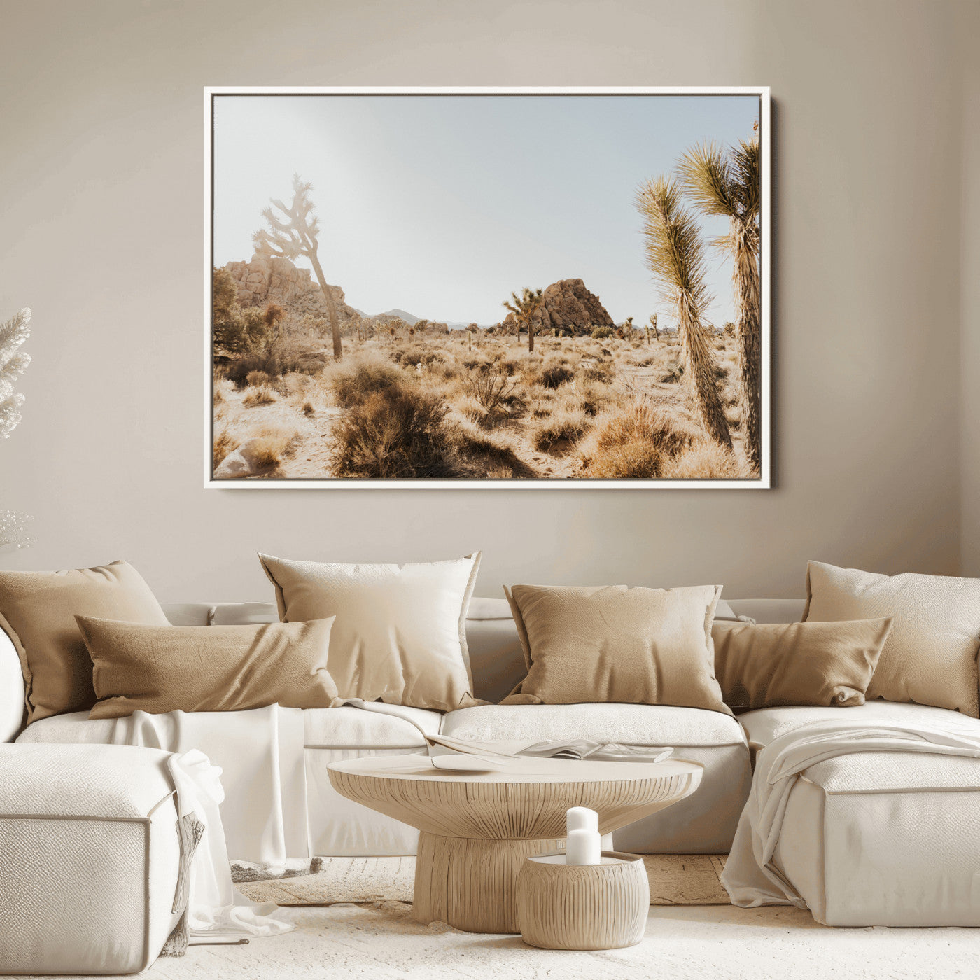 Sunlit desert landscape featuring Joshua trees, rocky formations, and dry bushes under a clear sky.
