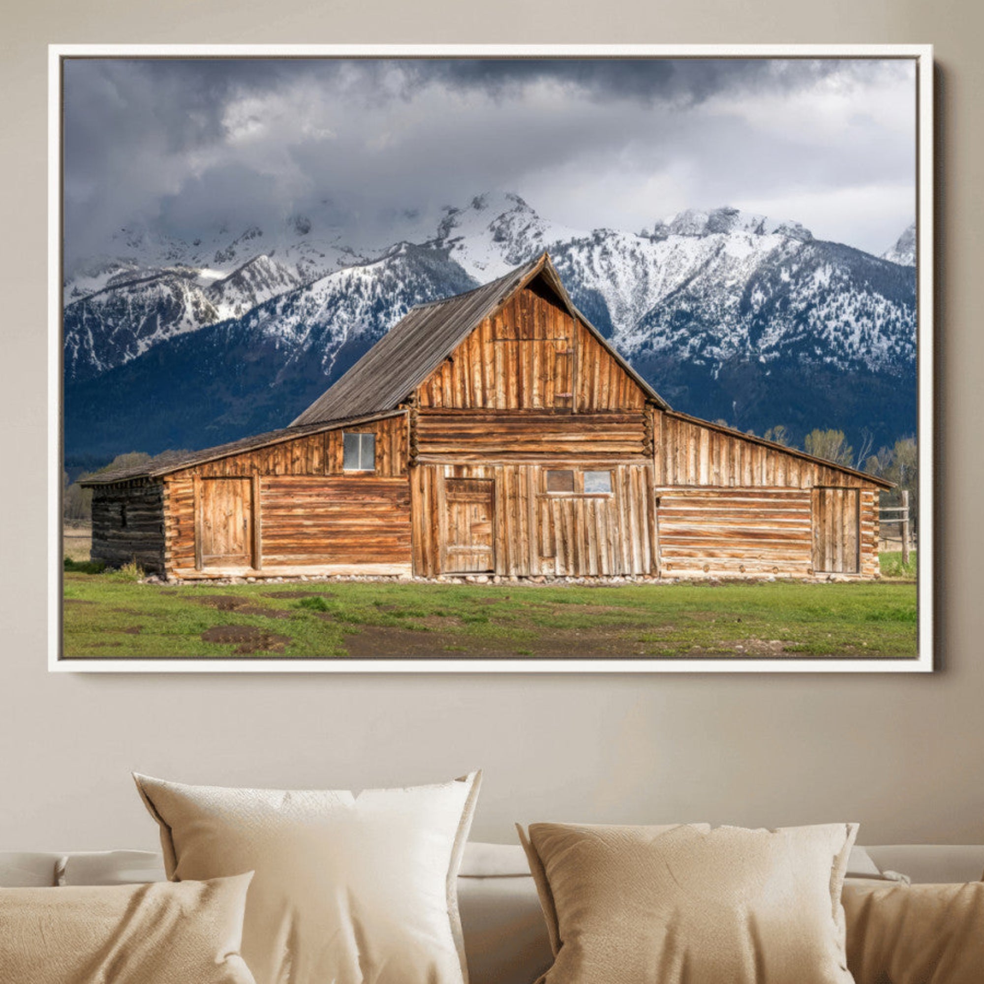 A stunning wall art canvas print featuring a rustic wooden barn set against a backdrop of snow-capped mountains under a dramatic cloudy sky, perfect for adding a touch of rural charm to any space.