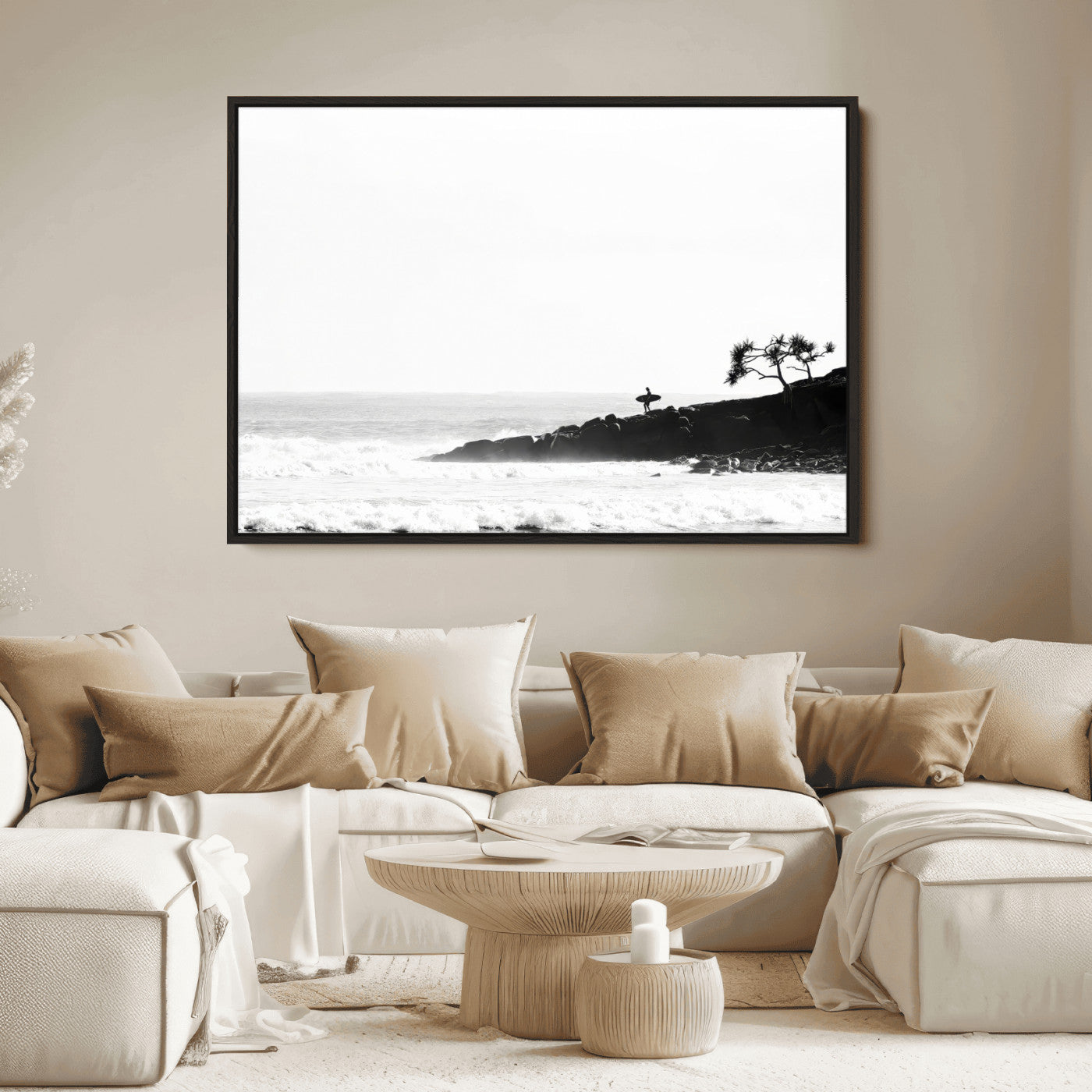 Black and white photo of a surfer standing on rocky cliffs, gazing at the waves, embodying the spirit of adventure and solitude.