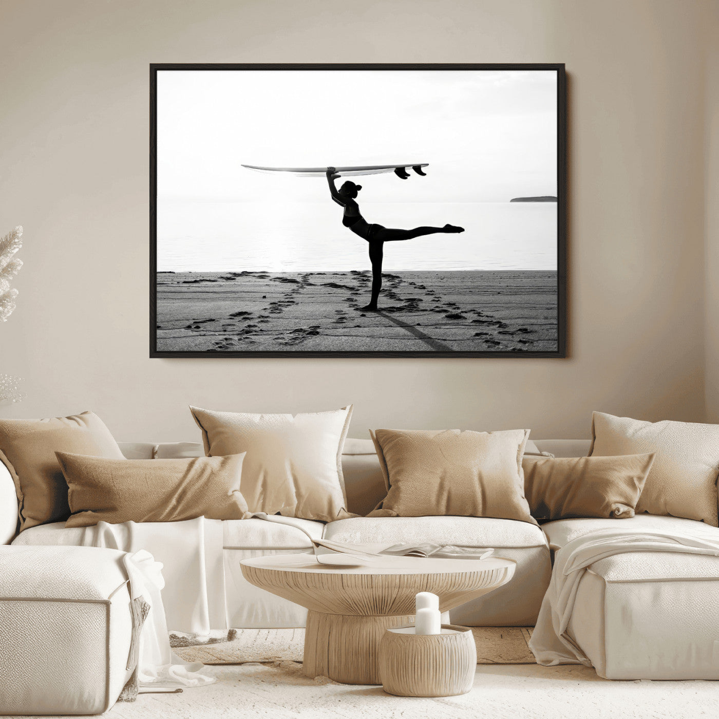 A woman balances a surfboard on her head while striking a yoga pose on the beach, silhouetted against a calm ocean horizon.