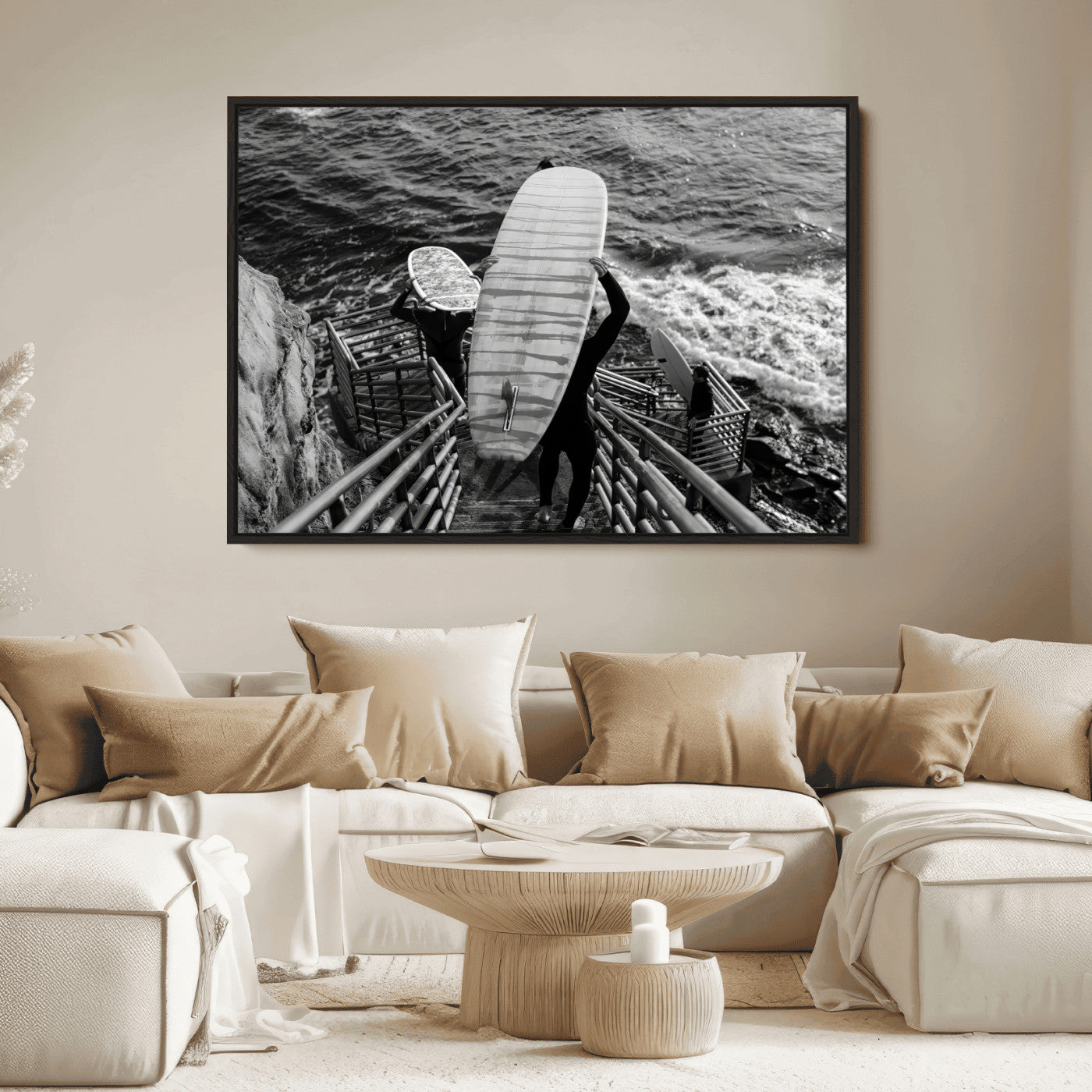 Black and white photo of surfers carrying boards down a rugged cliffside stairway, capturing a bold and adventurous coastal scene.