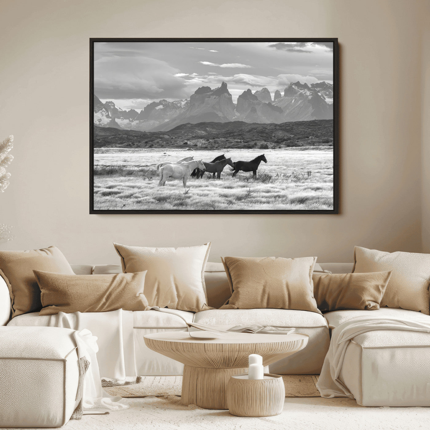 A black and white landscape of wild horses grazing in a vast grassland with towering mountains in the background, creating a moody and rustic western aesthetic.