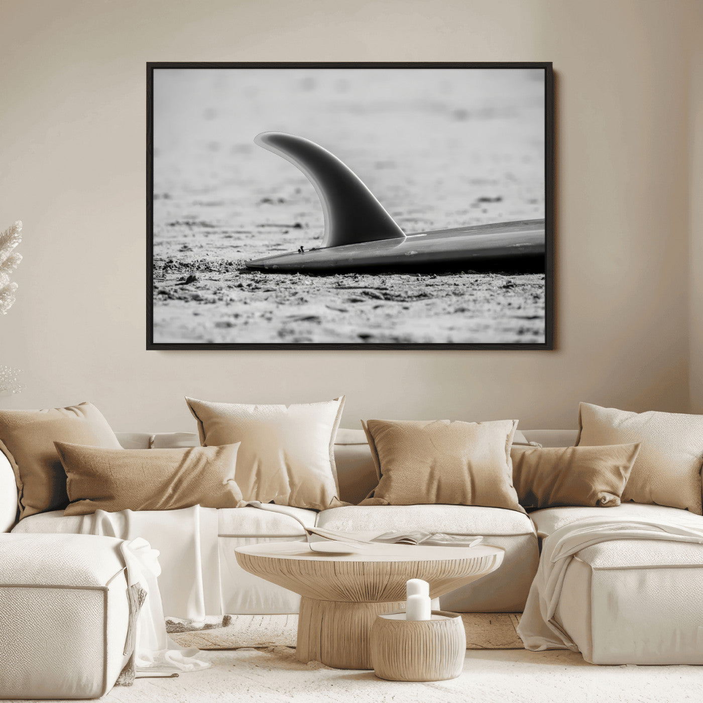 A black and white close-up of a surfboard fin resting on the sandy shore, highlighting minimalist beach aesthetics and classic surf culture.