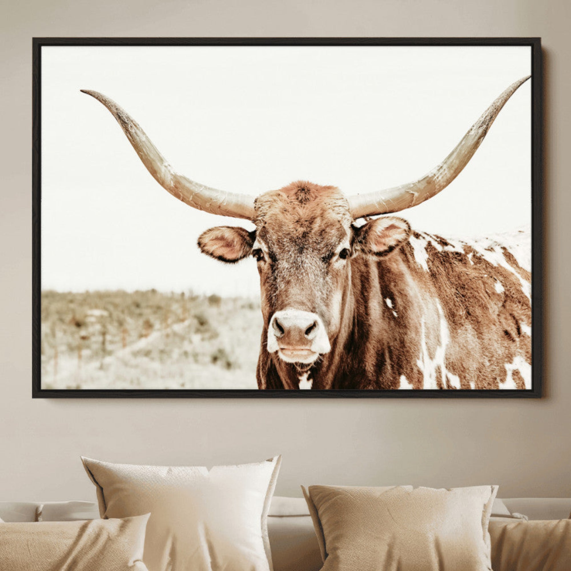 A Texas longhorn bull with wide horns, standing in a dry field under soft light, ideal for rustic farmhouse or western-themed interiors.