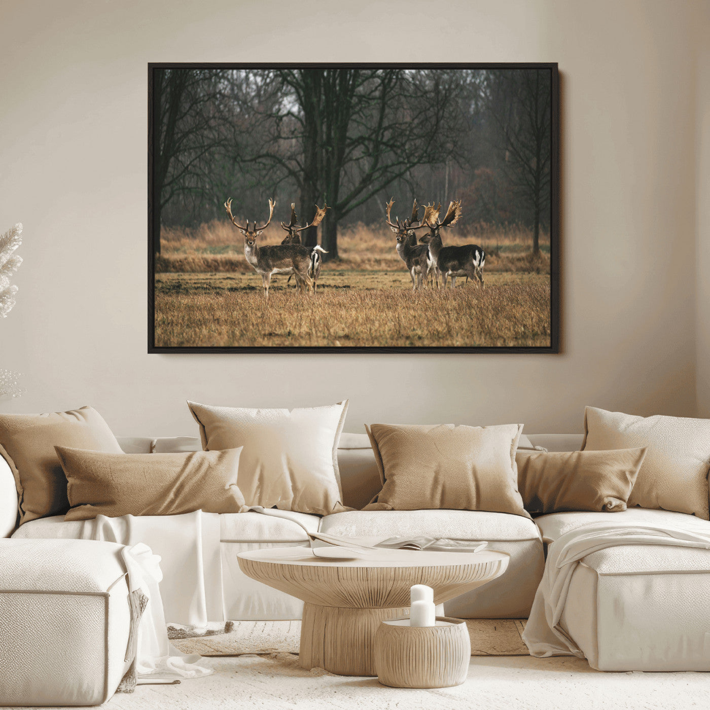 A group of majestic deer standing in a golden field with bare trees in the background, creating a peaceful woodland scene.