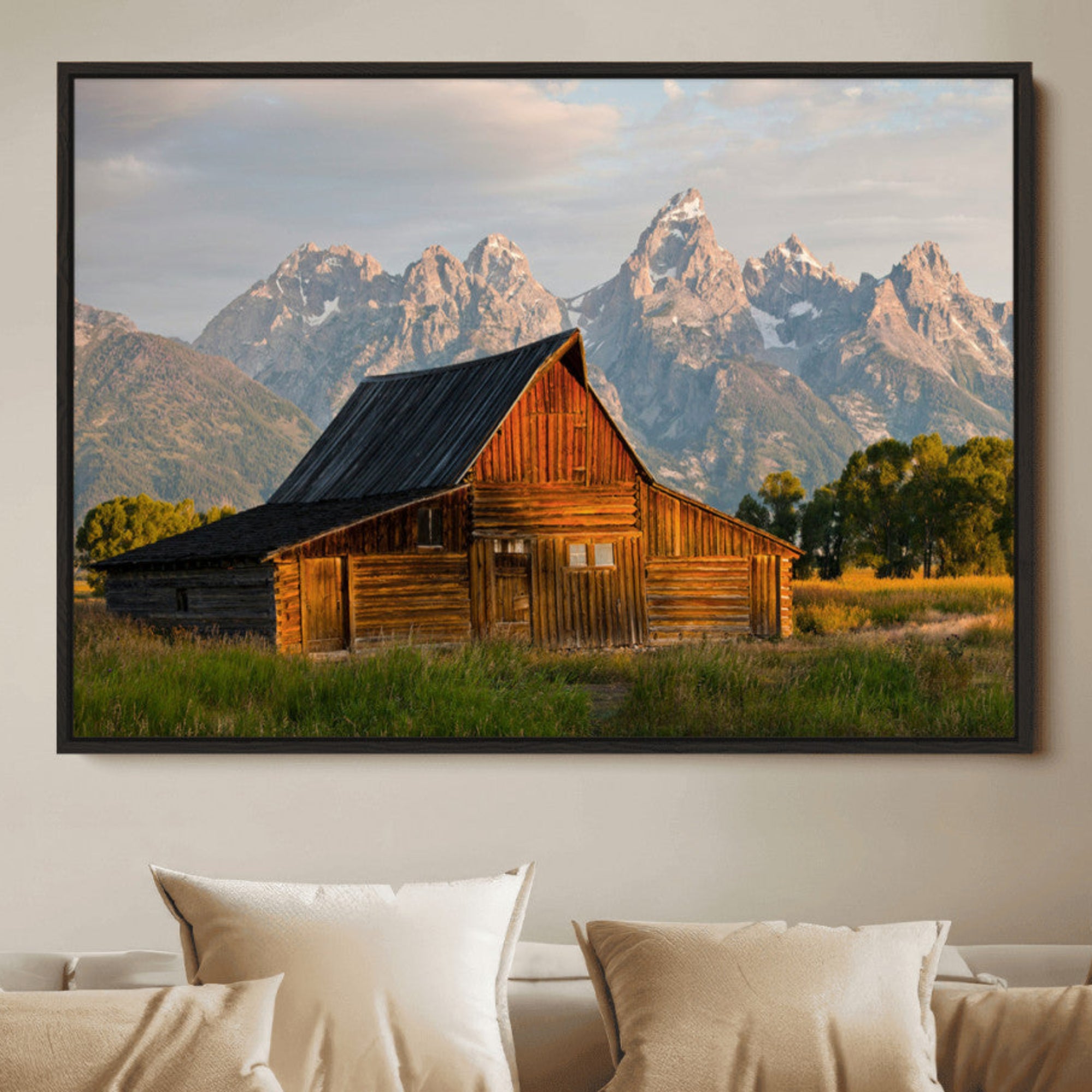 Rustic wooden barn set against towering mountain peaks under warm golden light, creating a peaceful Western countryside scene.