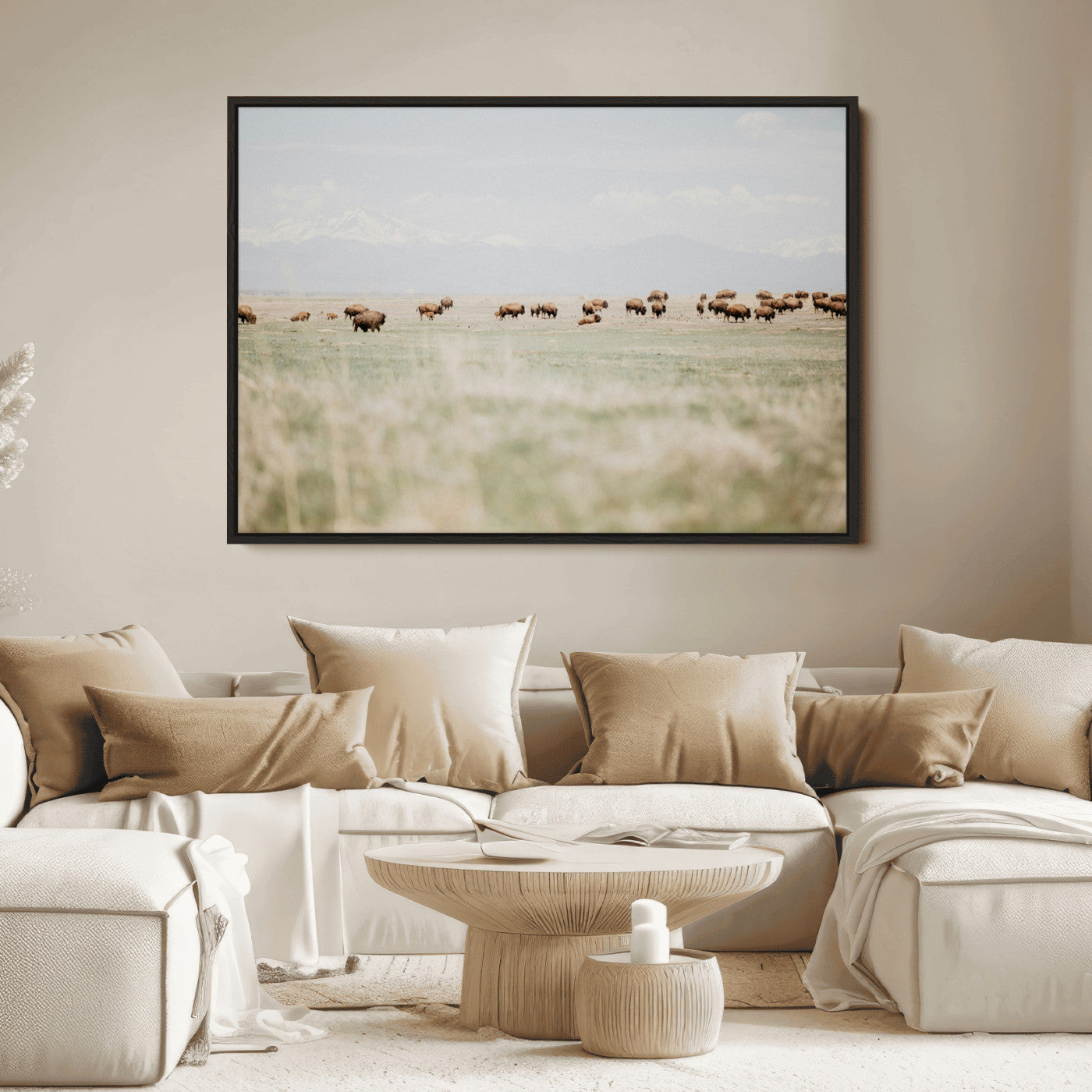 A herd of bison grazing in an open prairie with distant mountains under a soft sky, creating a serene and rustic Western landscape.