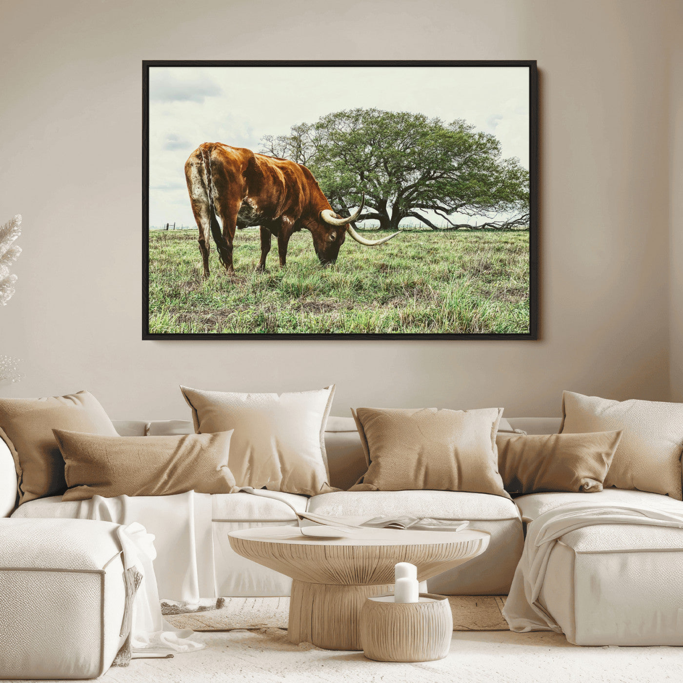 A Texas Longhorn grazing in a green pasture with a large tree in the background, evoking a rustic Western and farmhouse aesthetic.