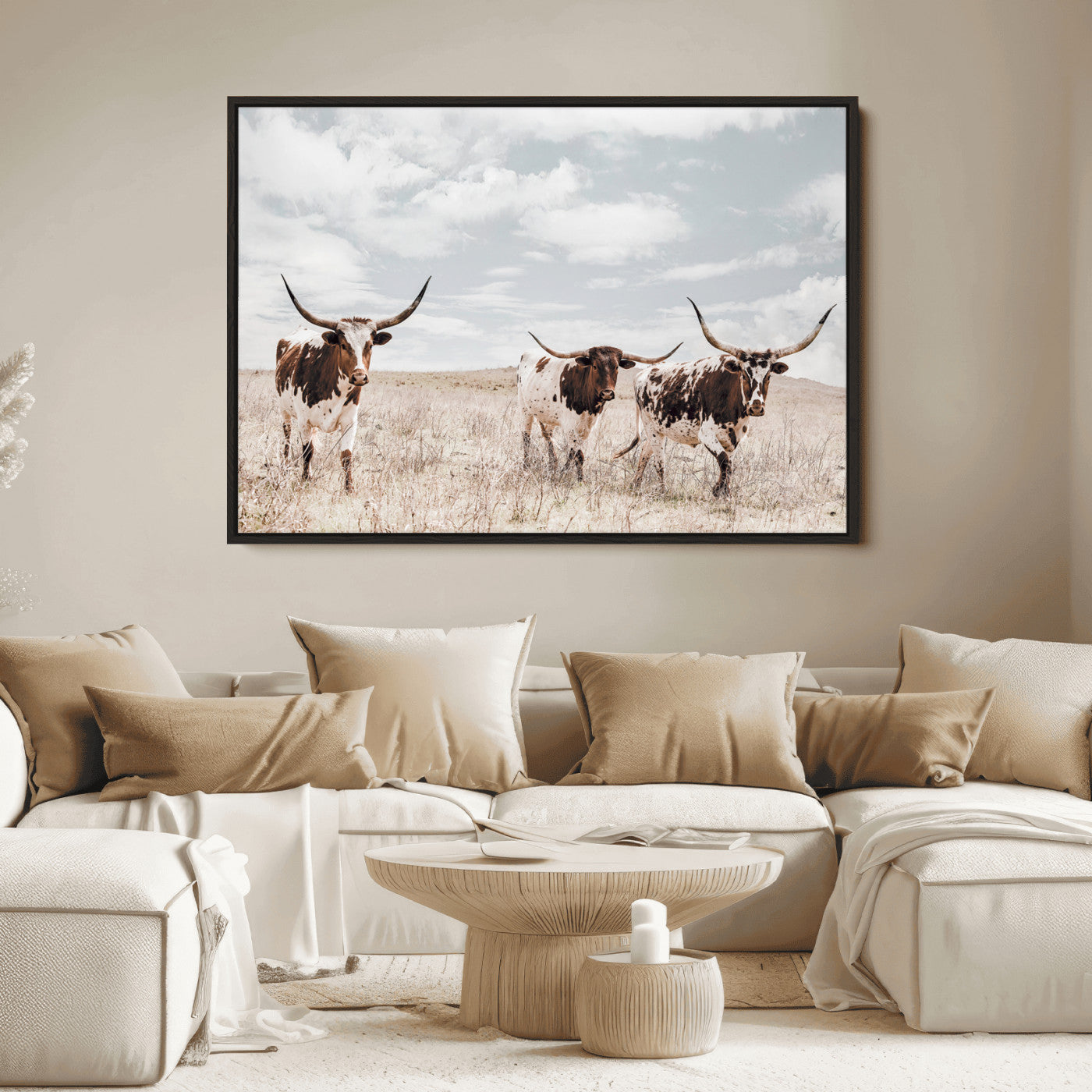 Three Texas Longhorn cattle walking through a dry grassy field under a partly cloudy sky.