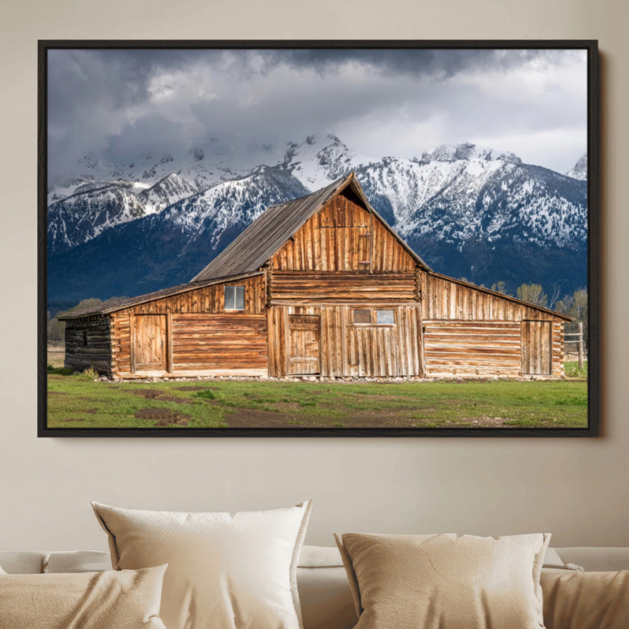 A stunning wall art canvas print featuring a rustic wooden barn set against a backdrop of snow-capped mountains under a dramatic cloudy sky, perfect for adding a touch of rural charm to any space.