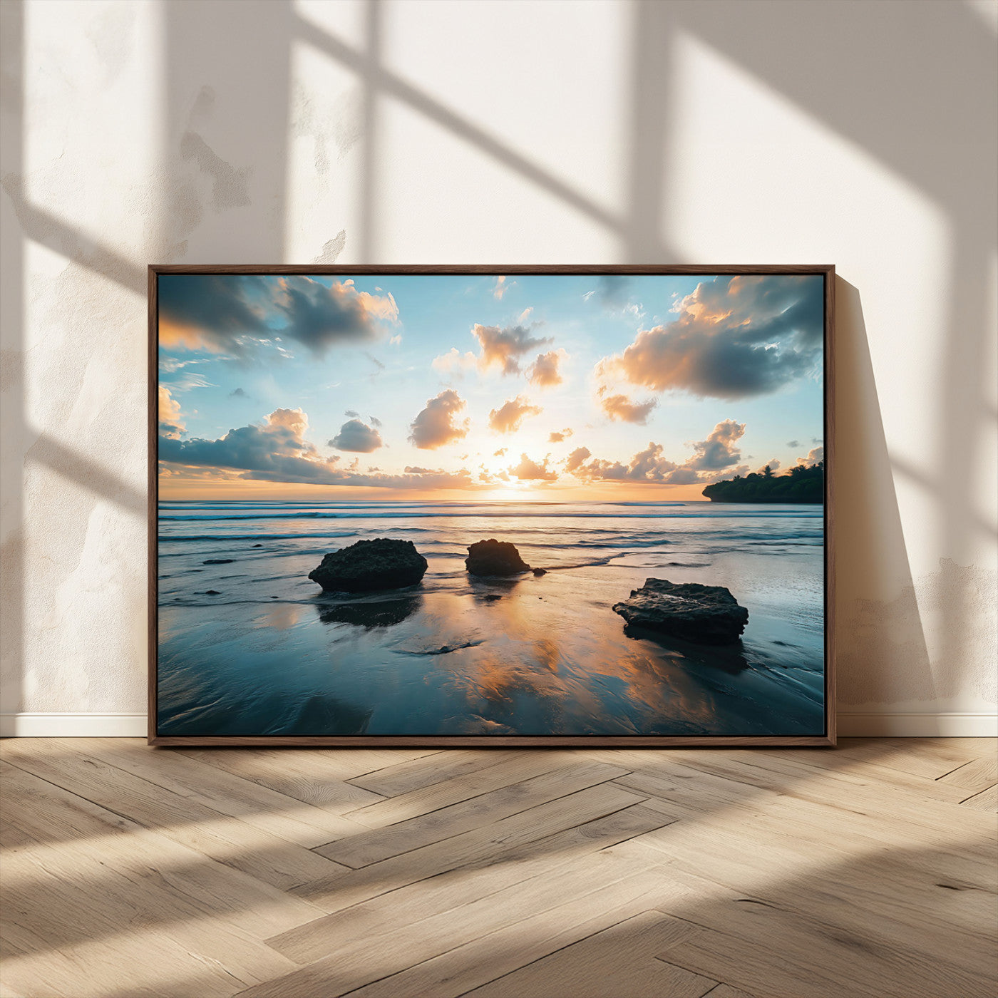 A serene beach at sunset with vibrant clouds, calm water, and rocks in the foreground reflecting the warm colors of the setting sun.