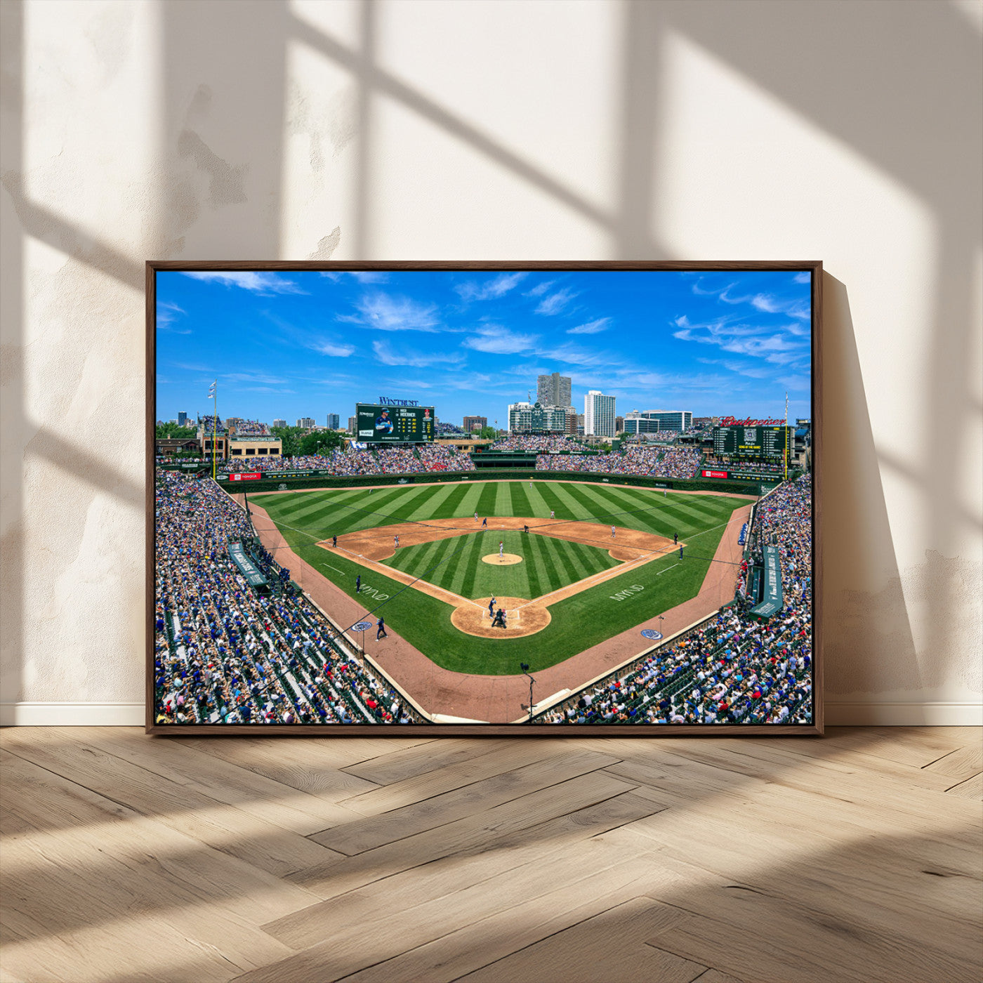 A wide-angle shot of a baseball field filled with spectators, with players on the field and the iconic Wrigley Field scoreboard in the background.