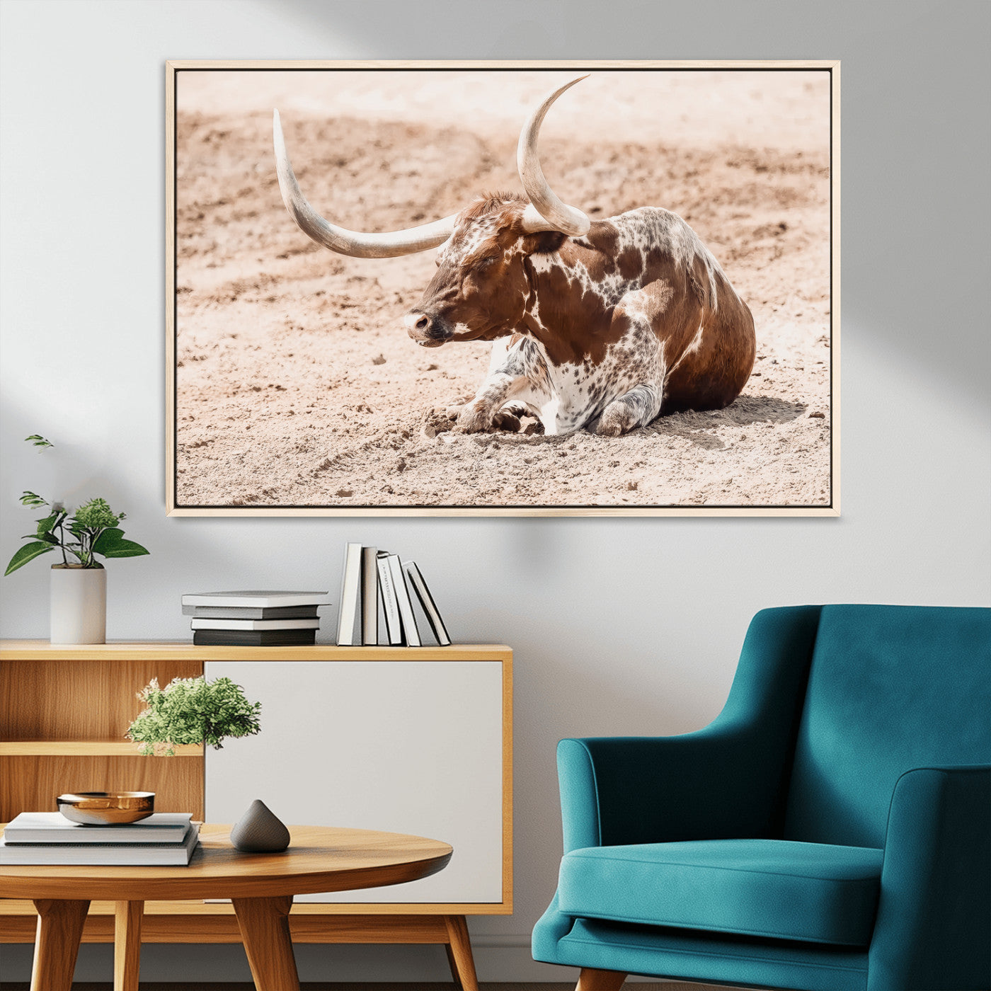 Texas Longhorn bull resting on dusty ground with warm tones, ideal for rustic western or farmhouse-themed wall decor.