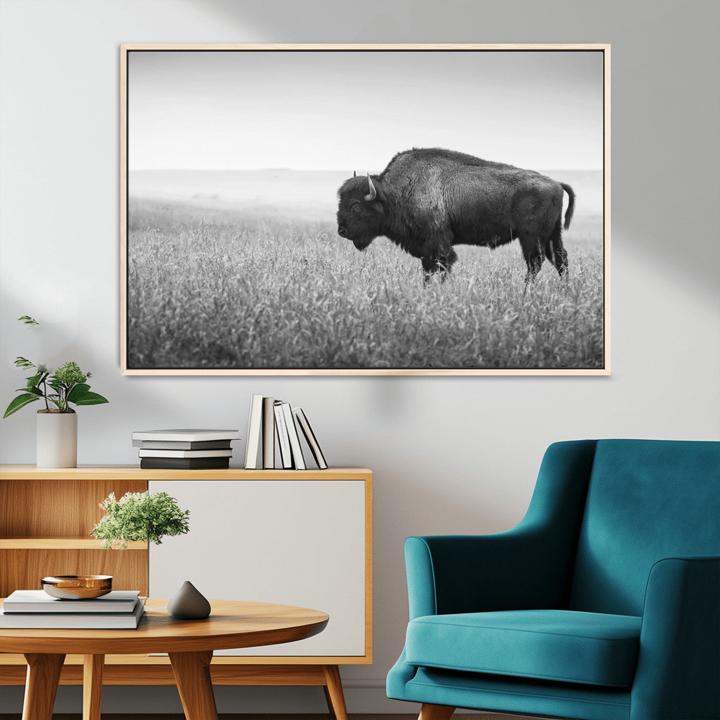 "Black and white image of a bison grazing in a vast field under an overcast sky."