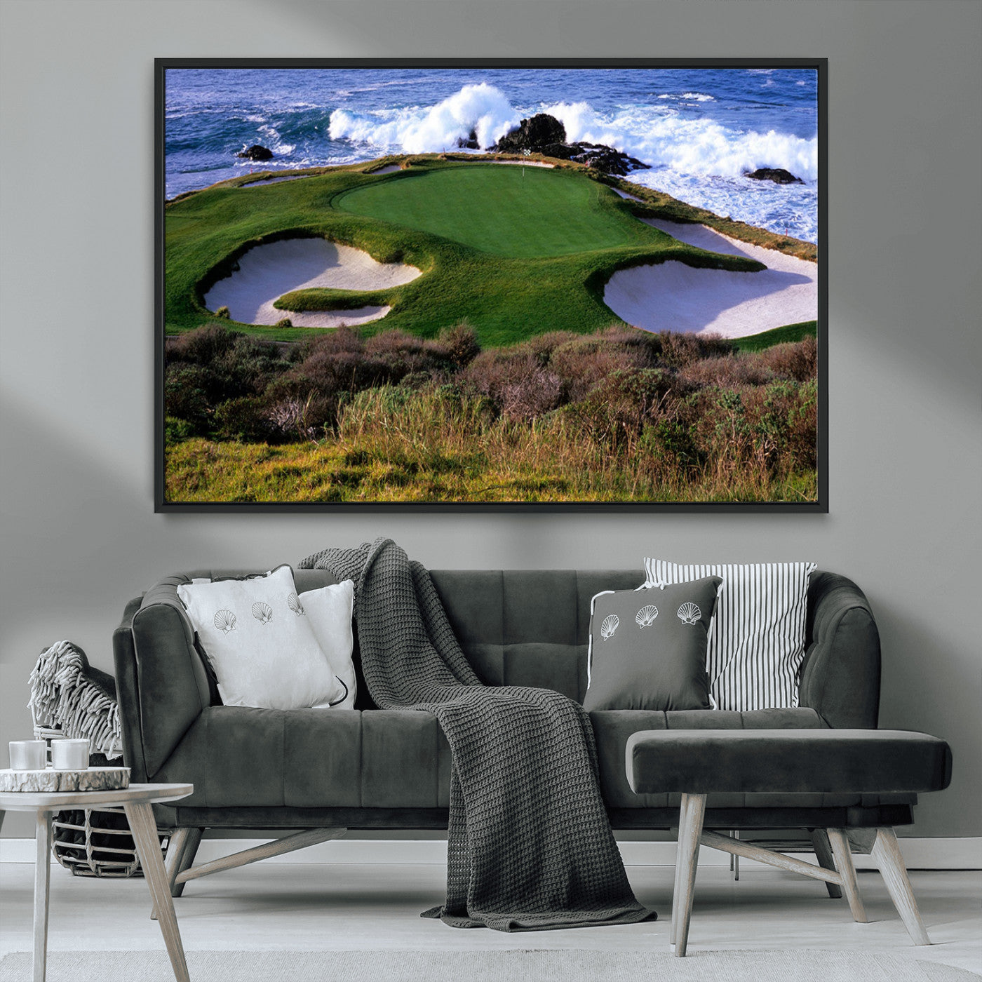 A scenic golf course located by the ocean, featuring a well-manicured green surrounded by sand traps and powerful ocean waves crashing on the shore.