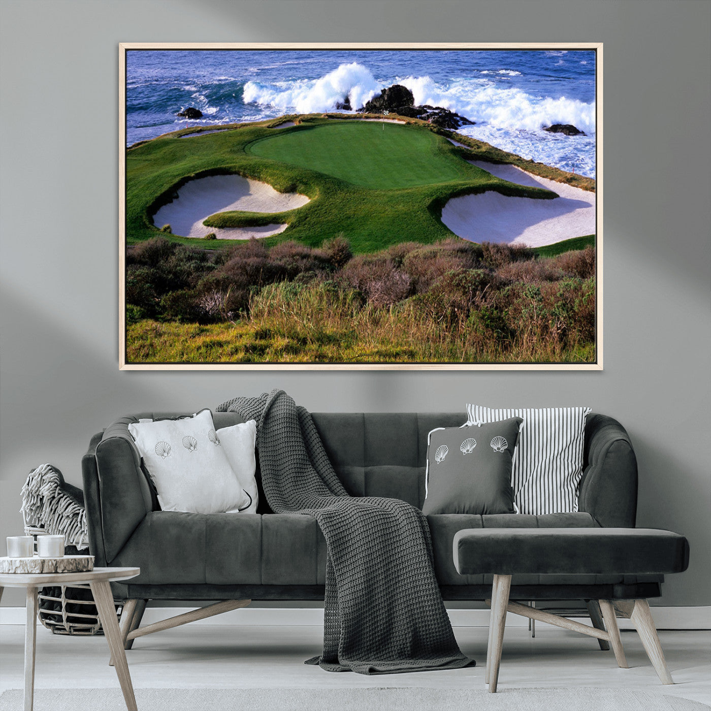 A scenic golf course located by the ocean, featuring a well-manicured green surrounded by sand traps and powerful ocean waves crashing on the shore.