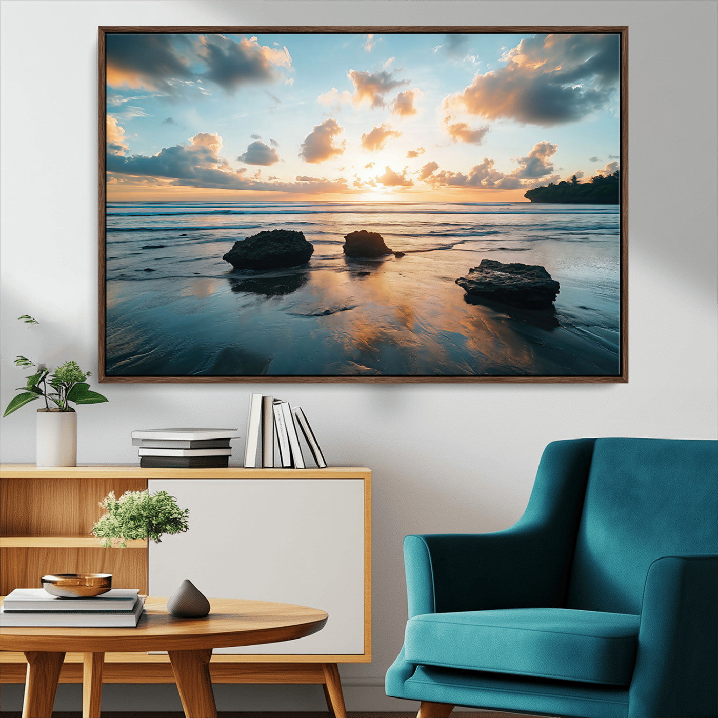 A serene beach at sunset with vibrant clouds, calm water, and rocks in the foreground reflecting the warm colors of the setting sun.
