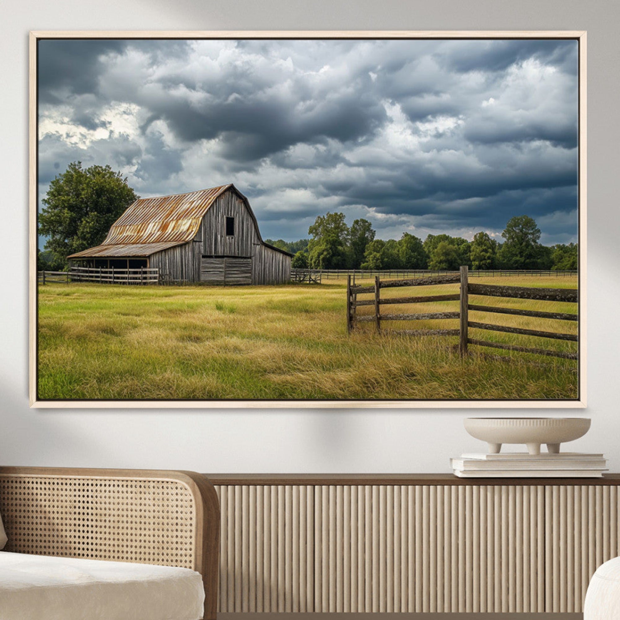 "Rustic barn in a wide open field under a dramatic sky with dark clouds, surrounded by a wooden fence and lush green trees."