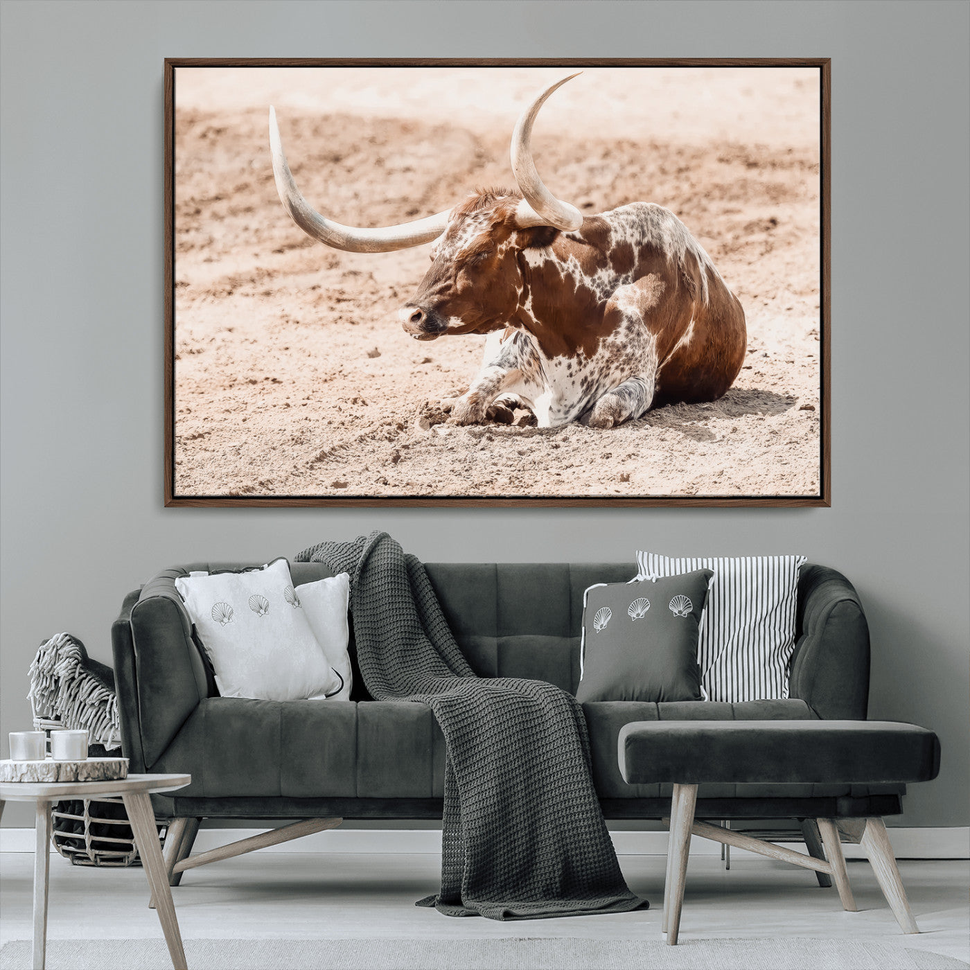 Texas Longhorn bull resting on dusty ground with warm tones, ideal for rustic western or farmhouse-themed wall decor.