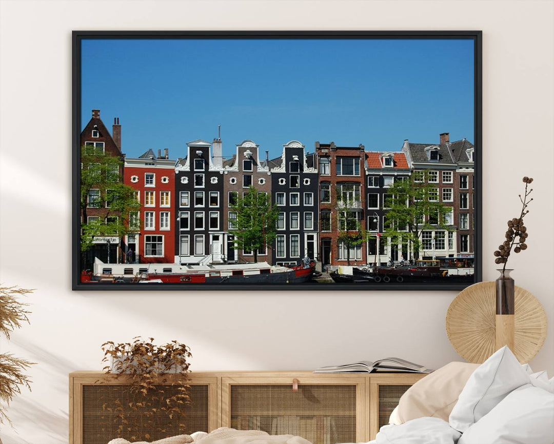 The Amsterdam City Wall Art Canvas Print showcases colorful traditional canal houses and boats set against a clear blue sky.