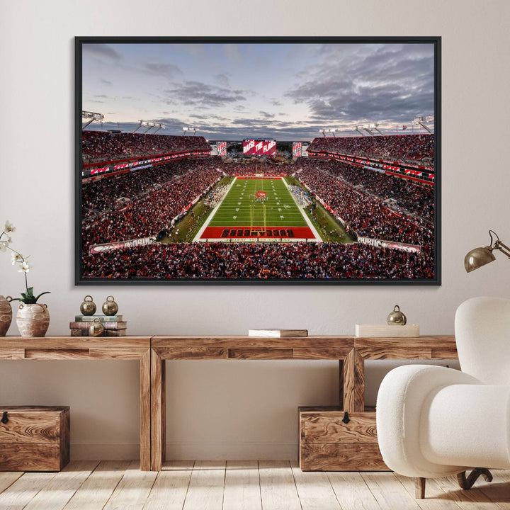 The wall art captures a stunning scene of Raymond James Stadium bathed in the warm hues of sunset. The sky, filled with clouds, provides a dramatic contrast to the vibrant lighting on the field, encapsulating the dynamic energy of a football game.