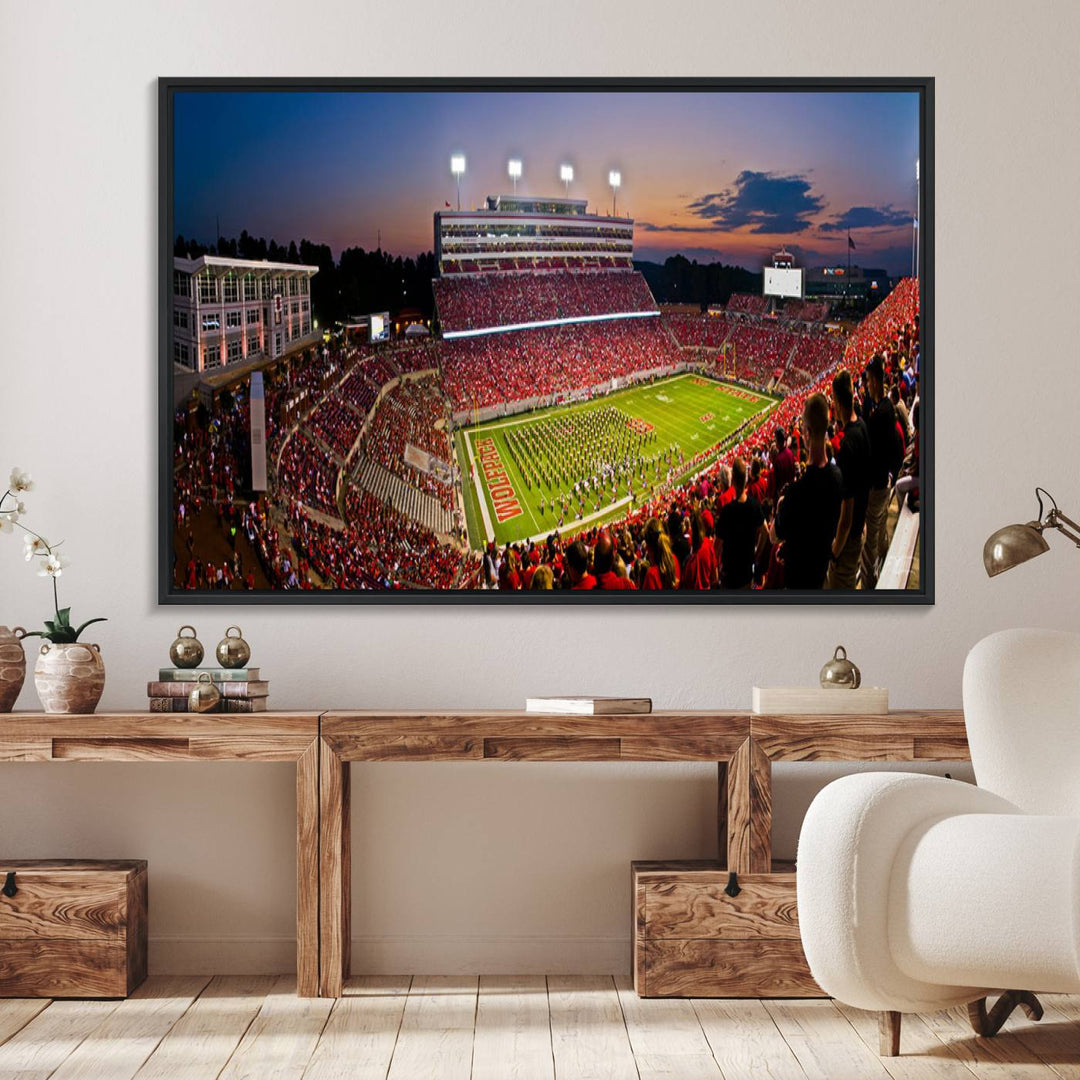 A print of a bustling Carter-Finley Stadium at dusk, featuring fans and a band, captures the essence of NC State Wolfpack football.