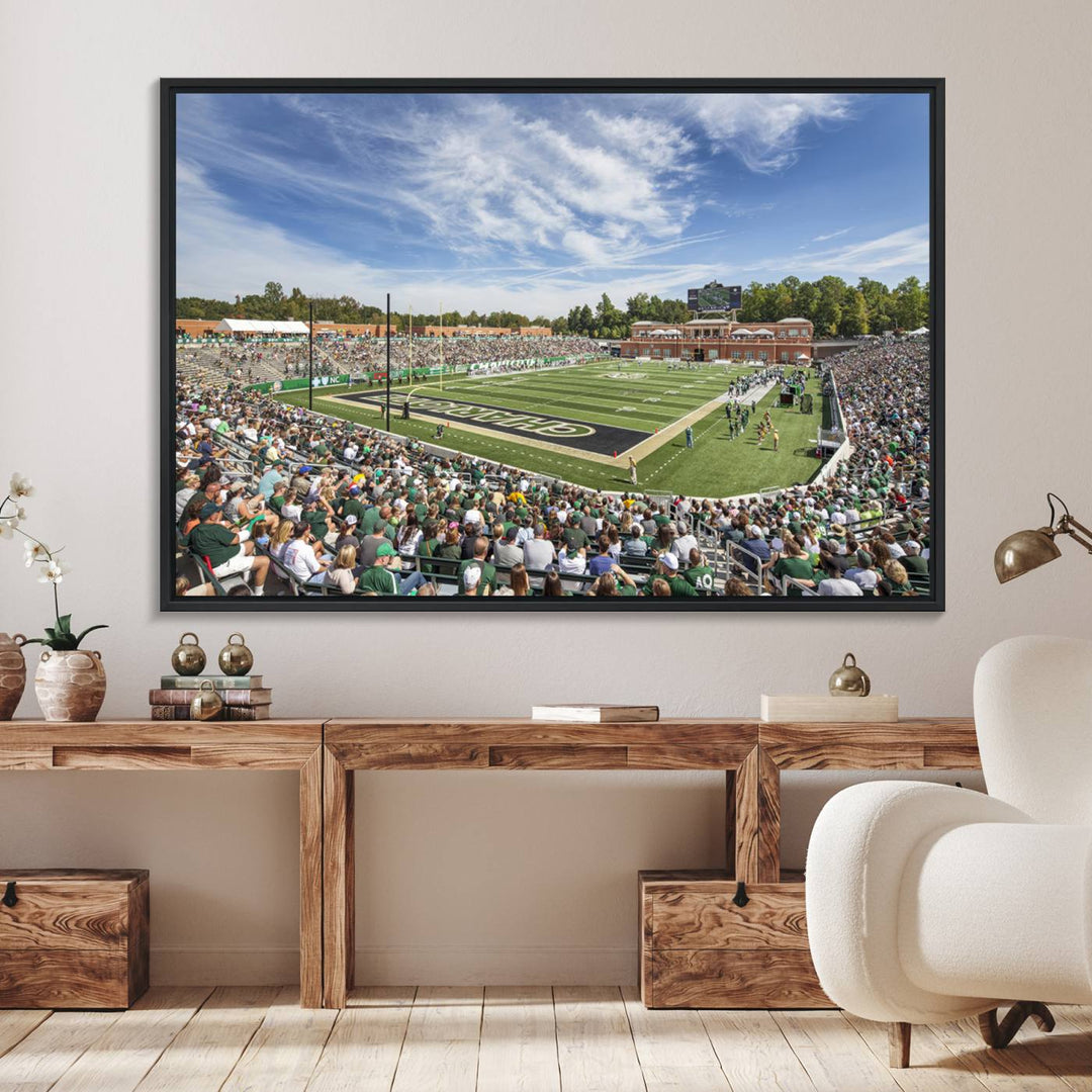 The University of Charlotte 49ers stadium print adds flair to a modern living room wall with its vibrant scene and clear sky.