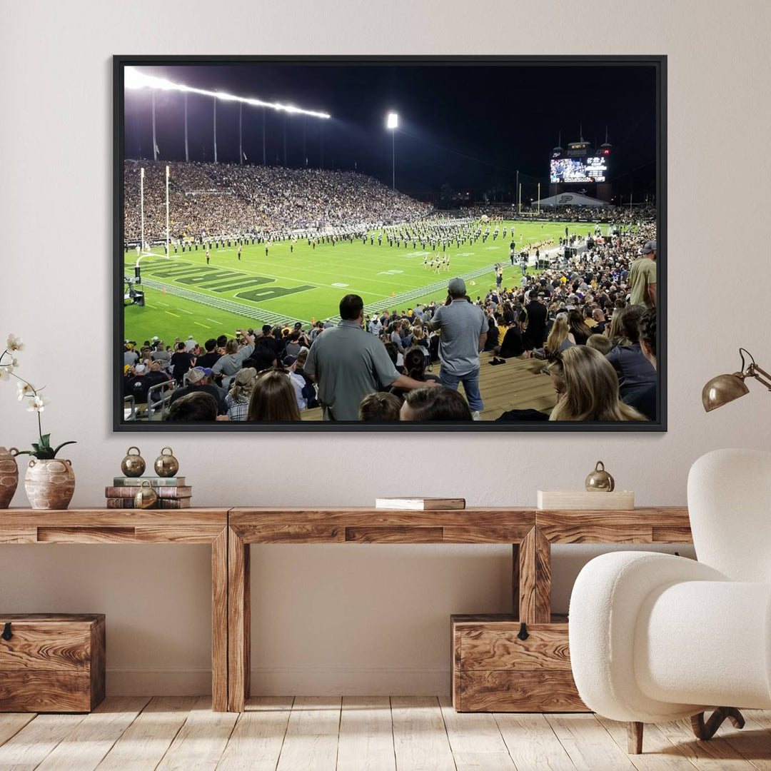 A painting depicting the Purdue Boilermakers football game at Ross-Ade Stadium is illuminated under gallery-quality lights.