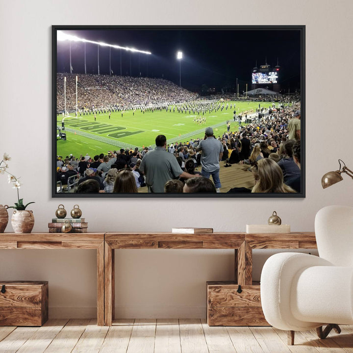 A painting depicting the Purdue Boilermakers football game at Ross-Ade Stadium is illuminated under gallery-quality lights.