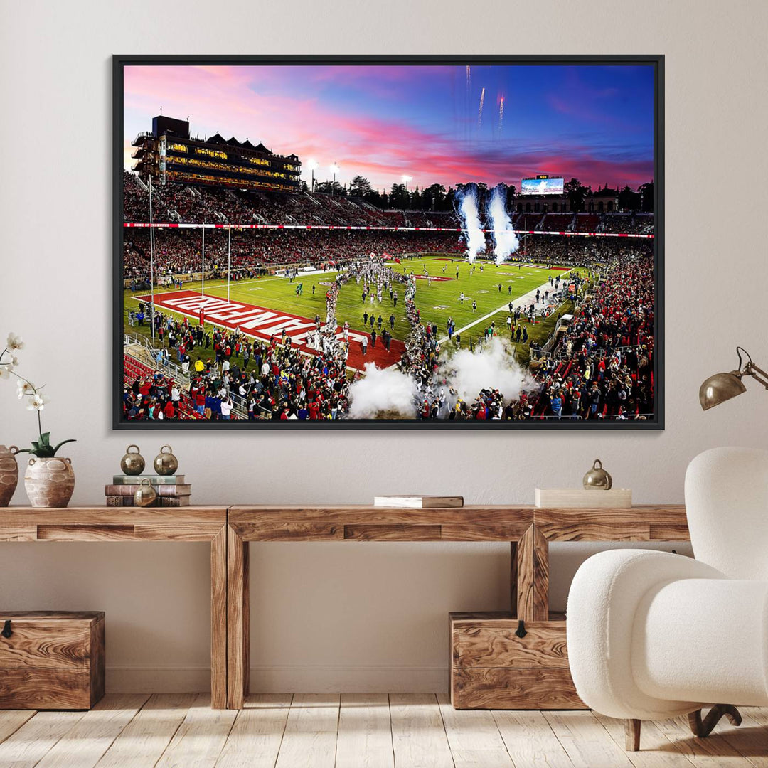 The wall art features a canvas print of the Stanford Cardinal football team, capturing players, fireworks, and smoke against the backdrop of a sunset at Stanford Stadium.