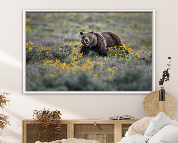 The "Grizzly 399 in Wild Flowers Wall Art Canvas Print" features a grizzly bear strolling through a field of yellow and purple flowers, beautifully showcased as a triptych. This handcrafted piece, proudly made in the USA, adds charm and sophistication to your space.