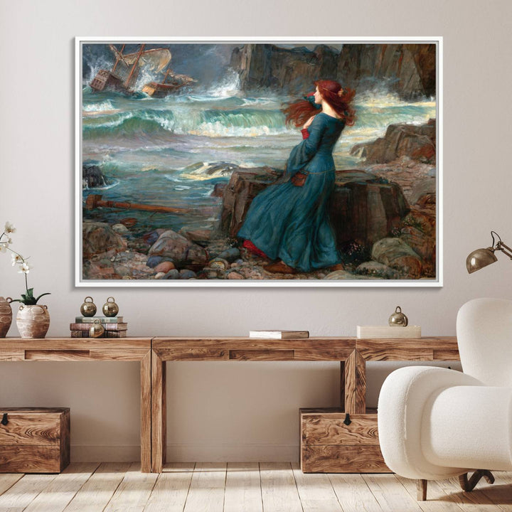 The Miranda by the Shore Wall Art Canvas Print depicts a woman in a blue dress standing by the sea, watching a shipwreck.