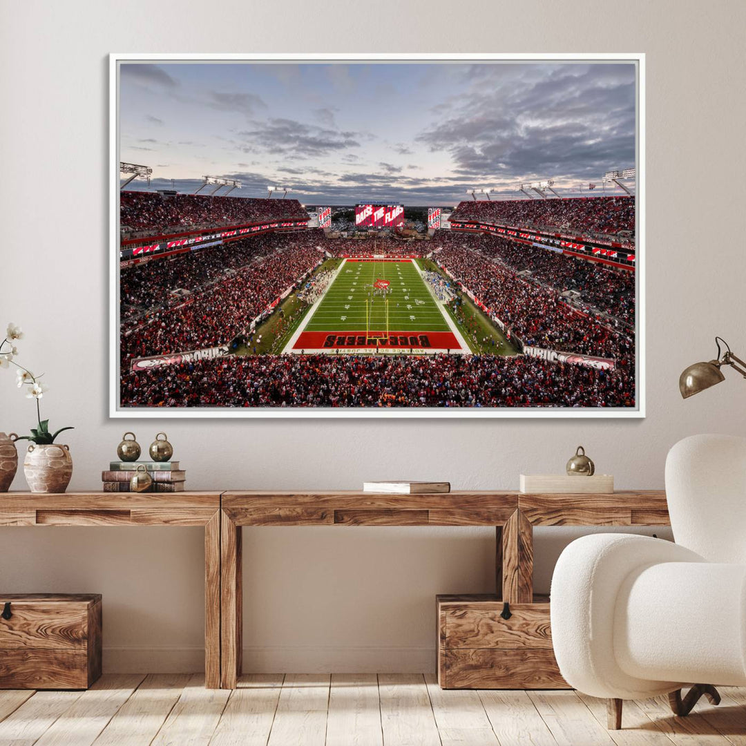 The wall art captures a stunning scene of Raymond James Stadium bathed in the warm hues of sunset. The sky, filled with clouds, provides a dramatic contrast to the vibrant lighting on the field, encapsulating the dynamic energy of a football game.