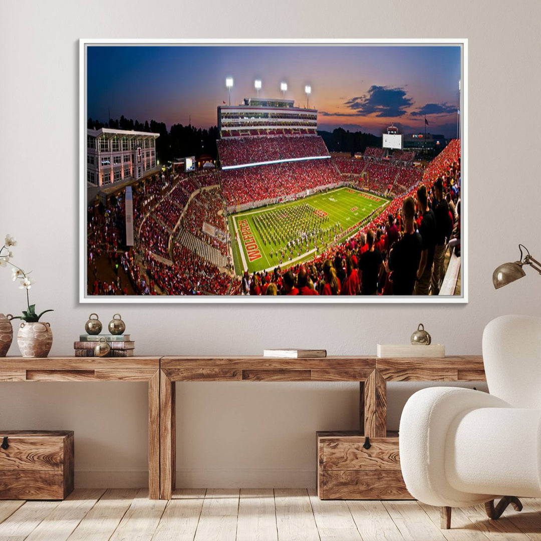 A print of a bustling Carter-Finley Stadium at dusk, featuring fans and a band, captures the essence of NC State Wolfpack football.