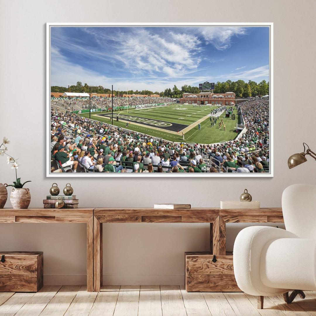 The University of Charlotte 49ers stadium print adds flair to a modern living room wall with its vibrant scene and clear sky.