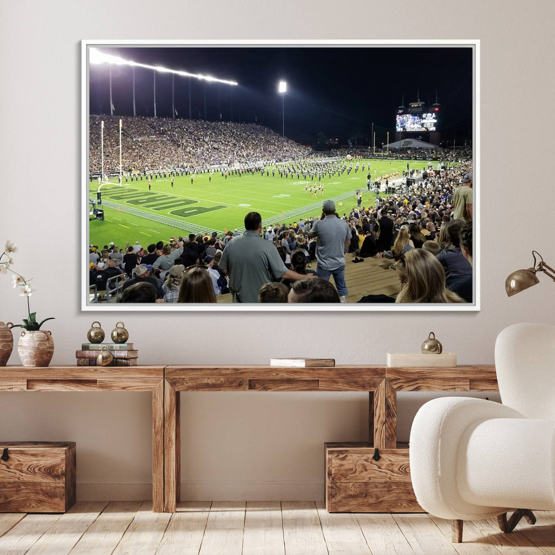 A painting depicting the Purdue Boilermakers football game at Ross-Ade Stadium is illuminated under gallery-quality lights.