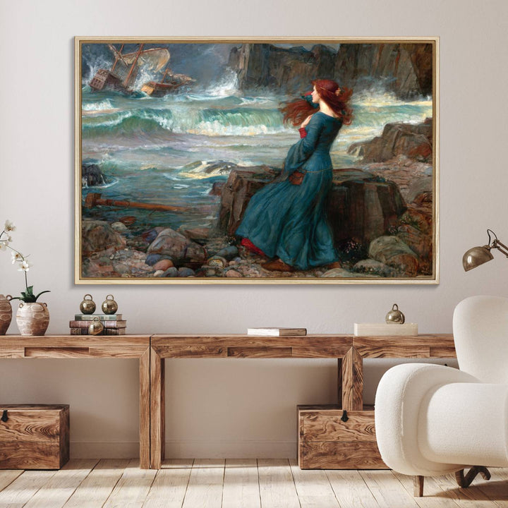 The Miranda by the Shore Wall Art Canvas Print depicts a woman in a blue dress standing by the sea, watching a shipwreck.