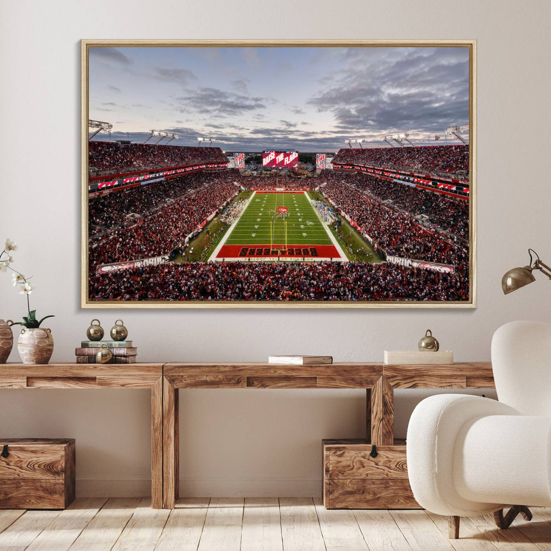 The wall art captures a stunning scene of Raymond James Stadium bathed in the warm hues of sunset. The sky, filled with clouds, provides a dramatic contrast to the vibrant lighting on the field, encapsulating the dynamic energy of a football game.