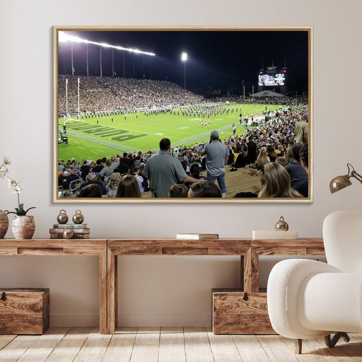 A painting depicting the Purdue Boilermakers football game at Ross-Ade Stadium is illuminated under gallery-quality lights.