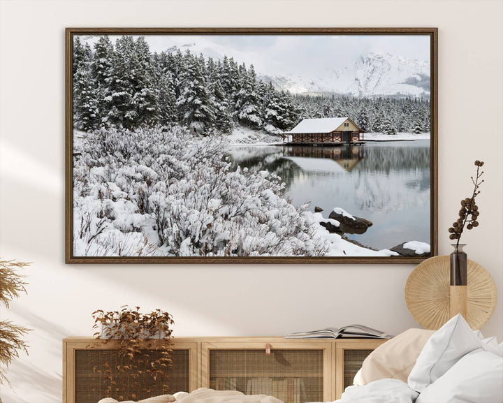 Experience the beauty of winter with the "Cabin by the Lake Canvas Wall Art," showcasing a serene snowy landscape. This rustic nature decor features a cozy cabin nestled amid snow-laden trees, set against a breathtaking mountain view, perfect for enhancing your living room.