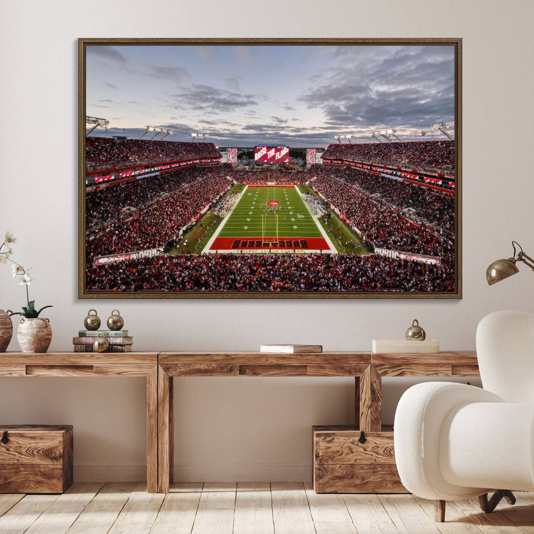 The wall art captures a stunning scene of Raymond James Stadium bathed in the warm hues of sunset. The sky, filled with clouds, provides a dramatic contrast to the vibrant lighting on the field, encapsulating the dynamic energy of a football game.