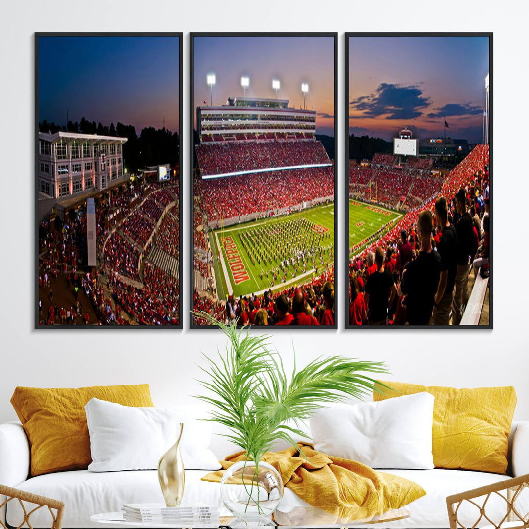 A print of a bustling Carter-Finley Stadium at dusk, featuring fans and a band, captures the essence of NC State Wolfpack football.