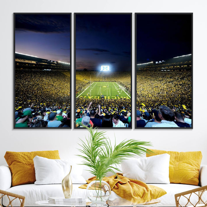 The wall art features a glowing M in this Michigan Wolverines Football Team Ann Arbor Stadium Canvas Print.