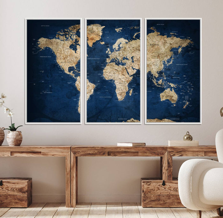 A large framed world map canvas print features beige landmasses set against a grunge-stained deep blue ocean background, creating an intriguing piece of wall art.