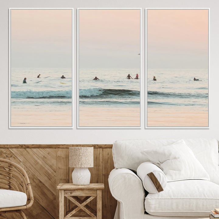 Dreamy photo of surfers waiting on soft pastel waves under a pink sunset sky, ideal for soft coastal minimalist or serene ocean-themed home decor.
