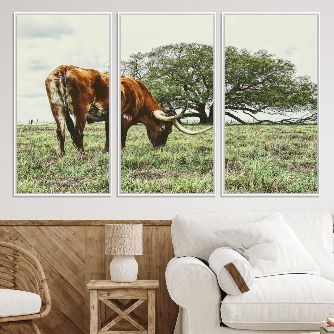 A Texas Longhorn grazing in a green pasture with a large tree in the background, evoking a rustic Western and farmhouse aesthetic.
