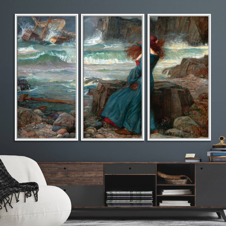 The Miranda by the Shore Wall Art Canvas Print depicts a woman in a blue dress standing by the sea, watching a shipwreck.